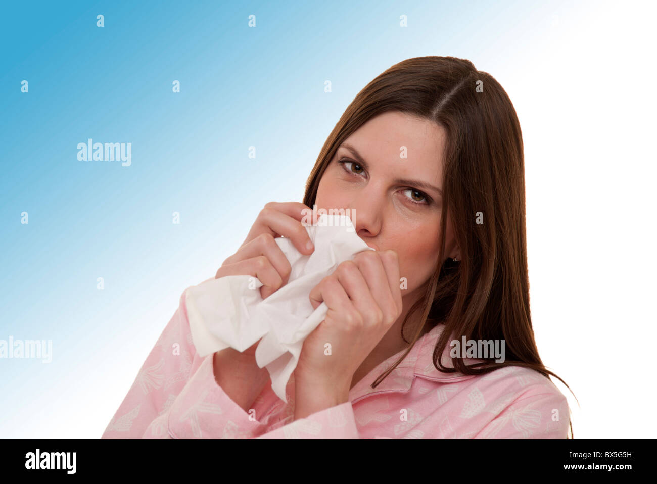 Brunette woman blowing her nose wearing pajamas Banque D'Images