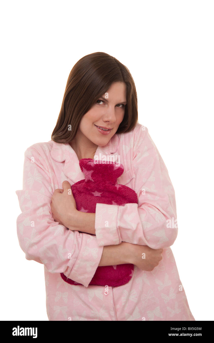 Brunette woman wearing pajamas serrant une bouteille d'eau chaude pour le confort et pour garder au chaud. Banque D'Images