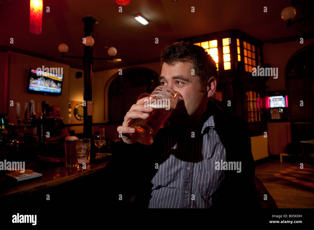 Un homme de boire une pinte de bière dans un pub, UK Banque D'Images