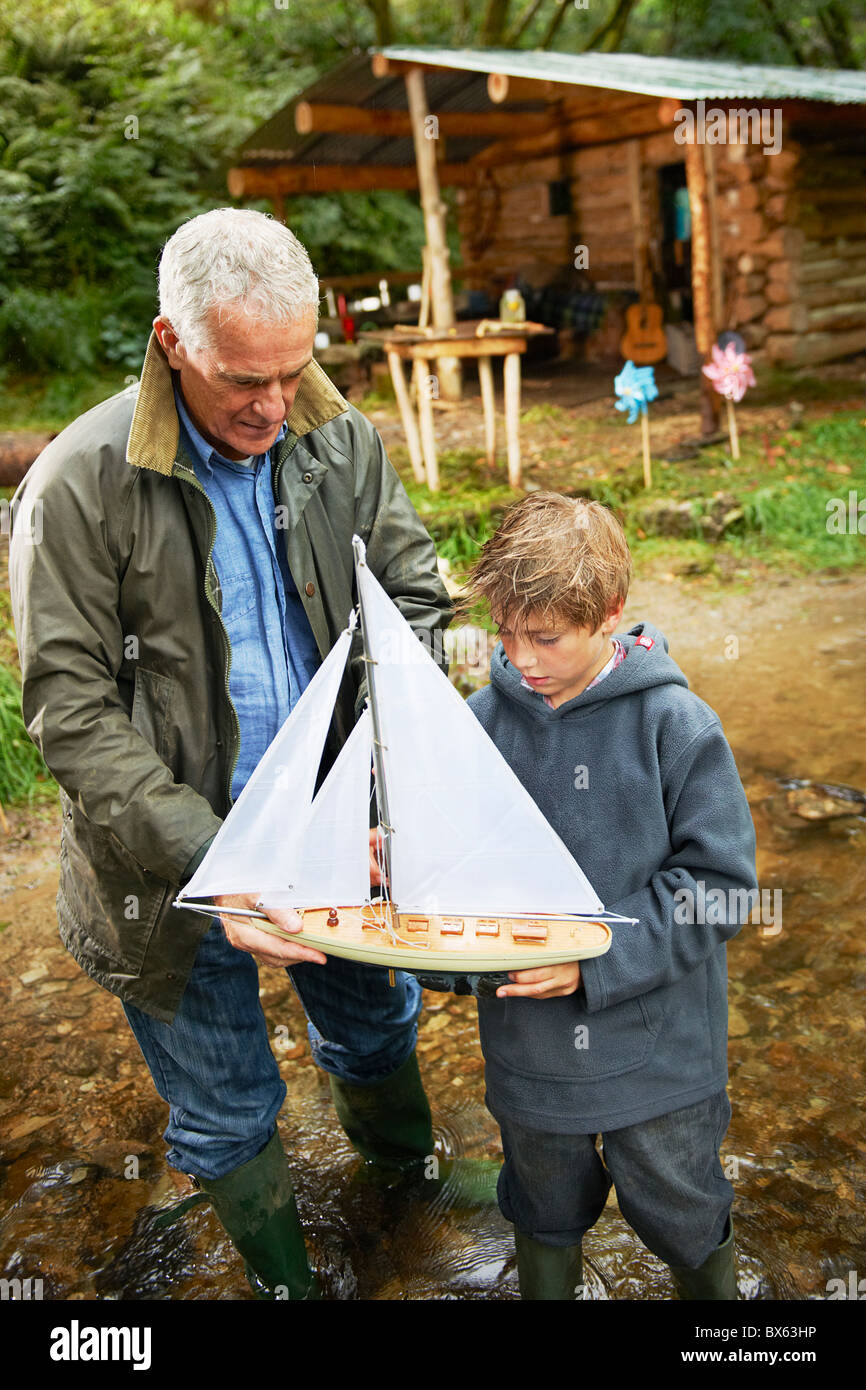 Grand-père et le garçon avec bateau à voile Banque D'Images
