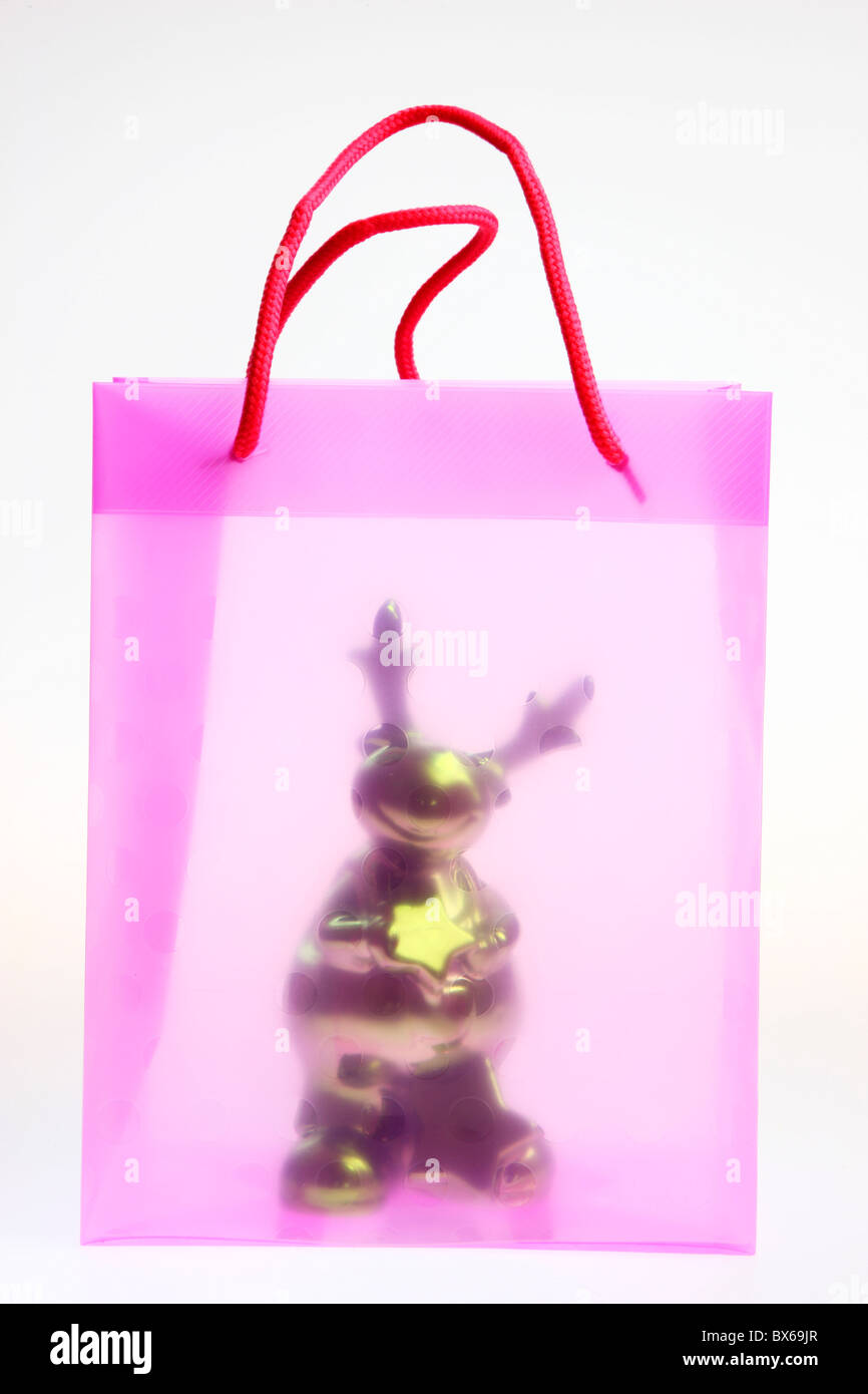 Rose et transparent, plastique, sac cadeau, avec un jouet de Noël figure. Banque D'Images