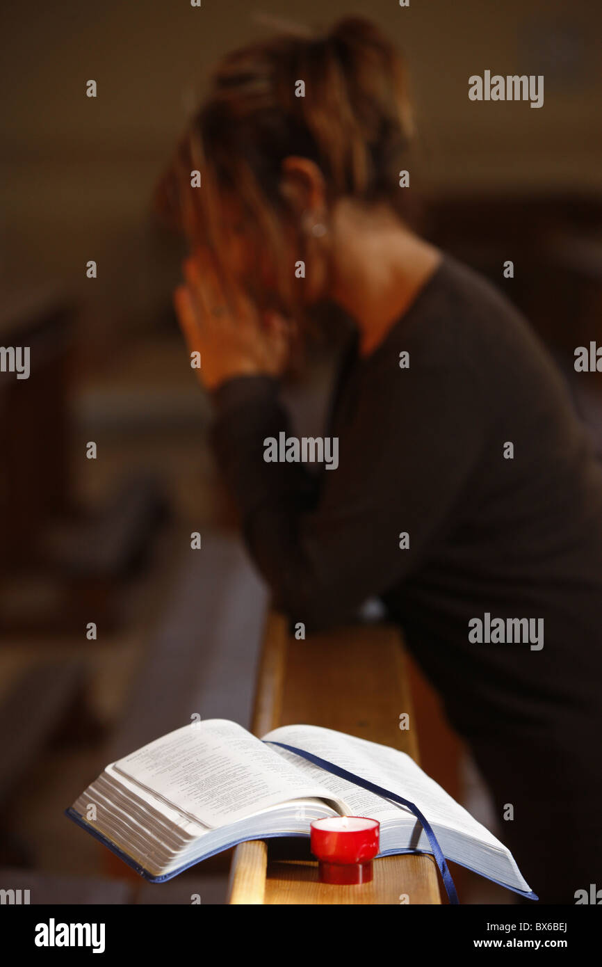 Bougie et Bible, avec femme en prière dans l'arrière-plan, Saint Nicolas de Veroce, Haute Savoie, France, Europe Banque D'Images