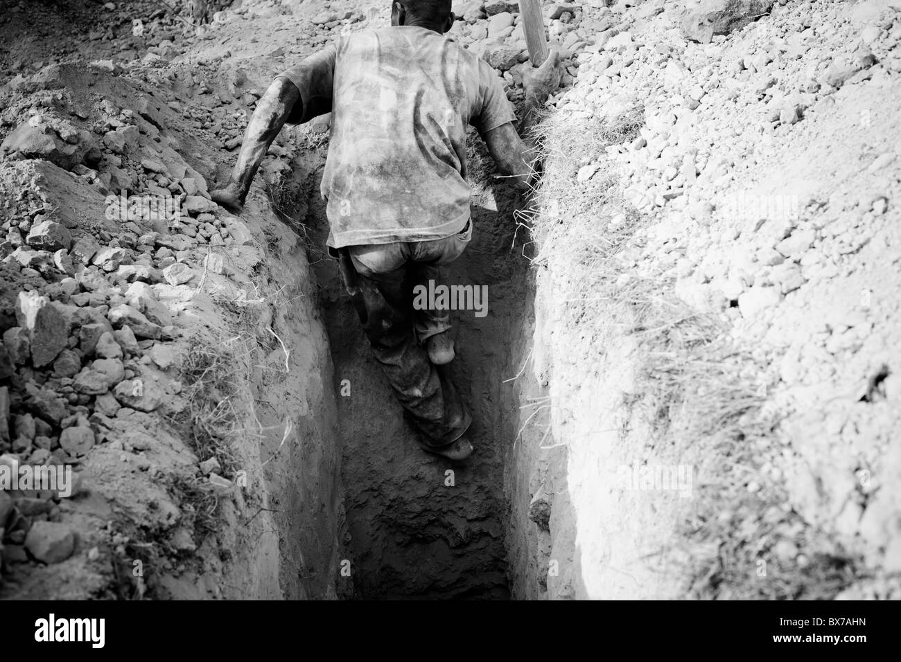 Un homme sort d'une fosse de latrines il est creusé au camp de Pétionville après le séisme en Haïti. Banque D'Images