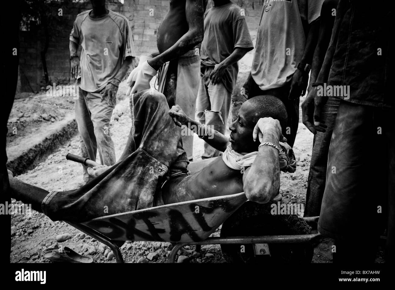 Les hommes de prendre une pause de creuser des fosses de latrines dans le camp de Pétionville après le séisme en Haïti. Banque D'Images