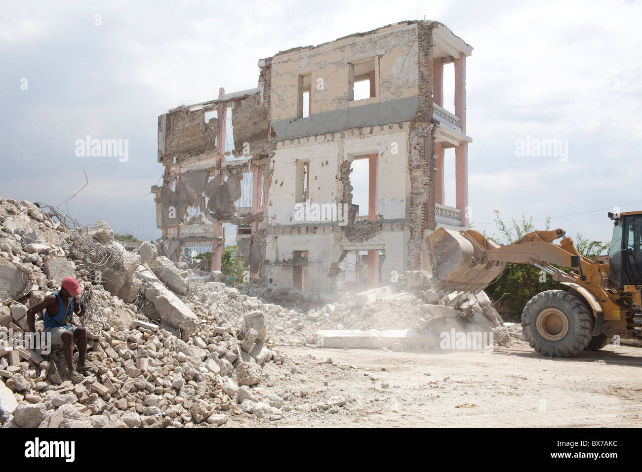 Les hommes travaillent à la main et avec l'équipement de construction pour dégager les décombres de bâtiments détruits dans le séisme en Haïti Banque D'Images