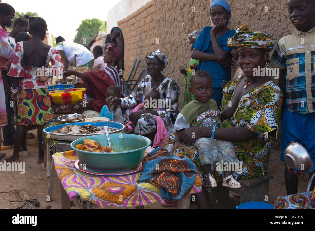 Les vendeurs de femelles avec leurs enfants la vente de self made foods sur un marché dans un village au Mali, Afrique de l'Ouest. Banque D'Images