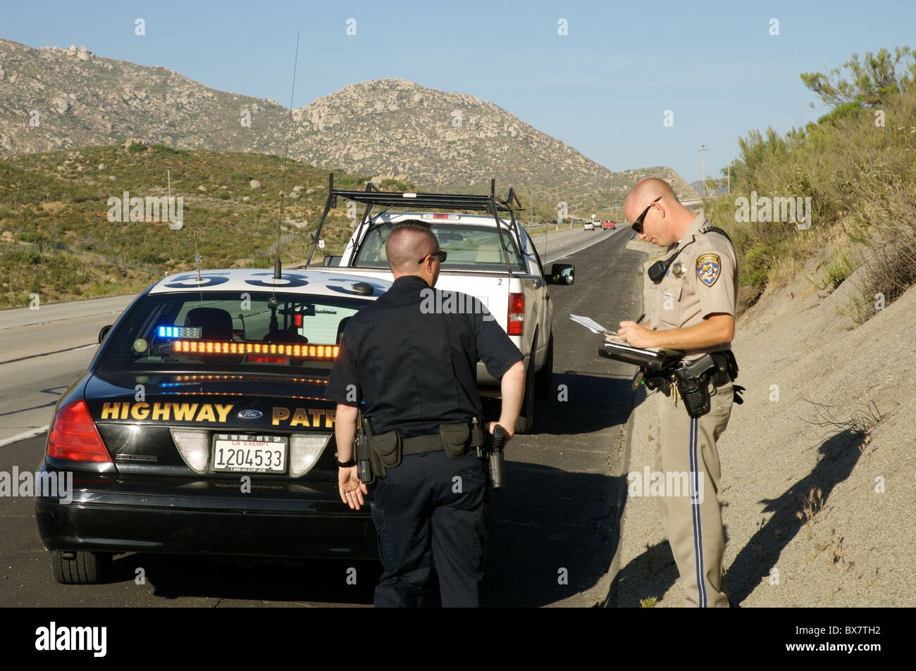 Un agent de la police locale aide un California Highway Patrol Officer sur un véhicule s'arrêter juste à l'est de San Diego. Banque D'Images