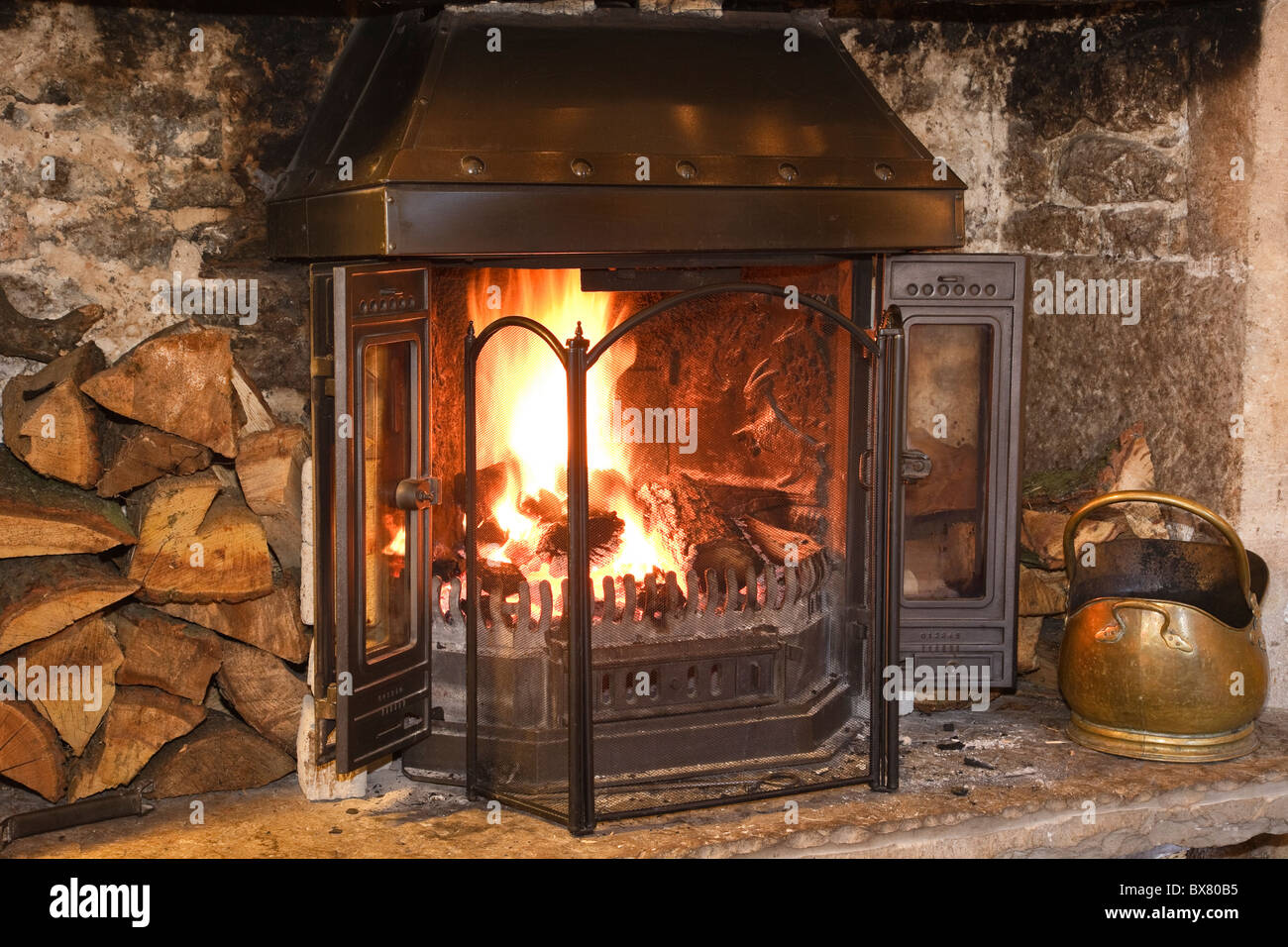 Cheminée avec bois et gravure fireguard sur le foyer dans un intérieur chaleureux salon. En Angleterre, Royaume-Uni, Angleterre Banque D'Images