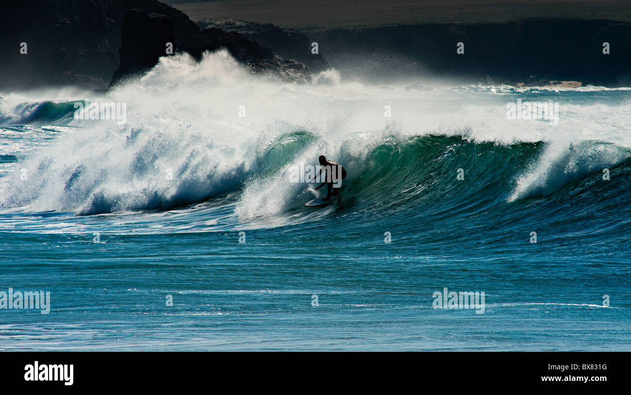 Un surfeur solitaire orageux en grandes vagues et pulvériser au large de la côte de Cornouailles, Angleterre Banque D'Images