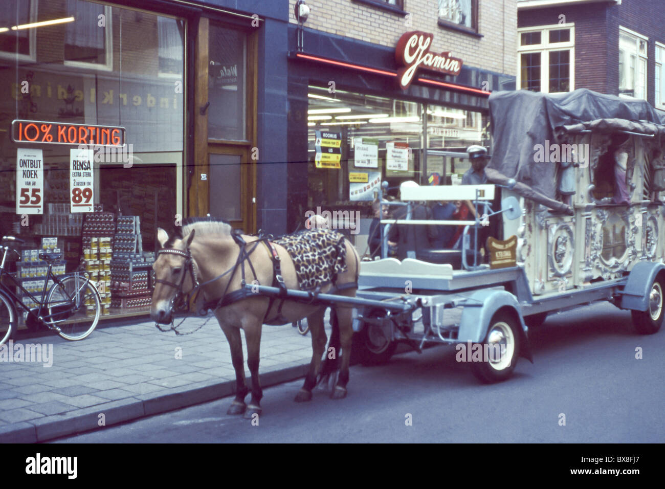 Une image originale des années 1960 montrant un cheval dessiné circus wagon qui s'arrête à l'extérieur d'un supermarché dans les Pays-Bas. Banque D'Images