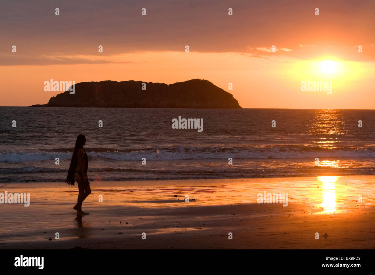 Personne qui marche sur la plage au coucher du soleil dans le Parc National Manuel Antonio en province de Puntarenas, Costa Rica. Banque D'Images