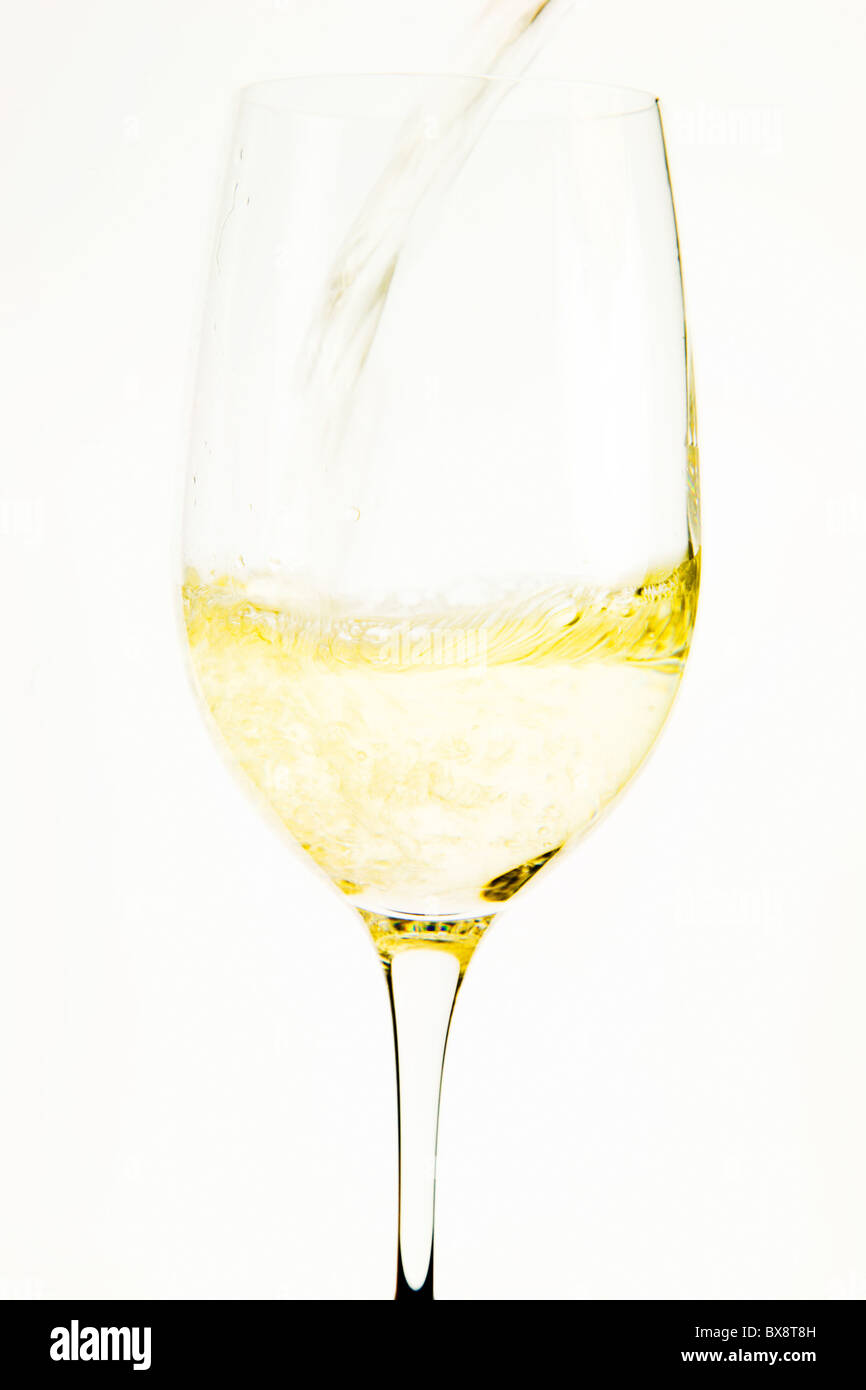 Verser le vin blanc dans un verre à dégustation Banque D'Images