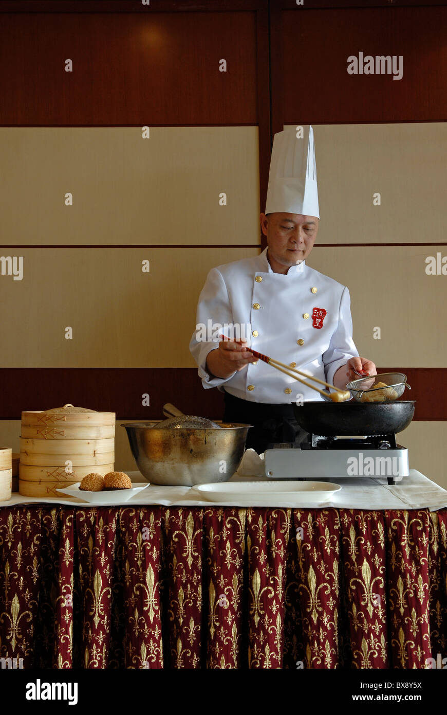 Un chef préparant des pâtisseries frites Jian DUI à base de farine de riz gluante et enrobées de graines de sésame servies dans un restaurant de Hong Kong Chine Banque D'Images