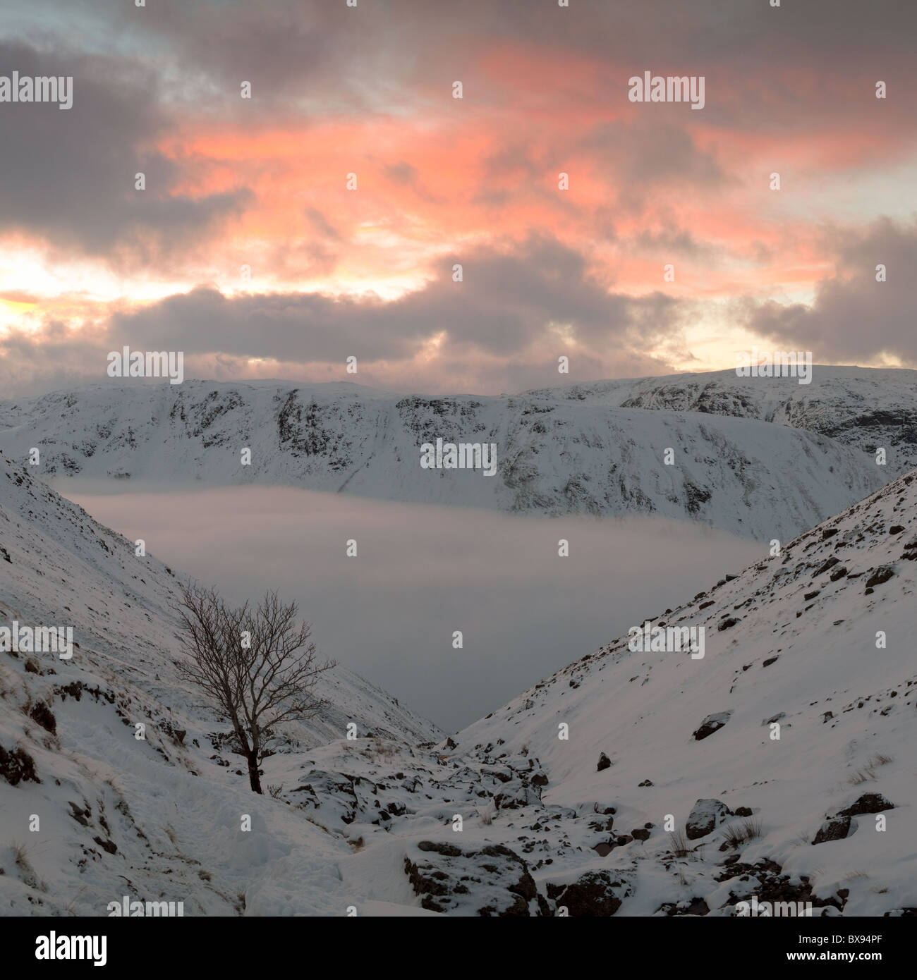 Pentes de neige descendant dans le cloud. Coucher de soleil sur l'inversion, Grizedale Tarn à l'acier a chuté, Lake District, UK. Banque D'Images