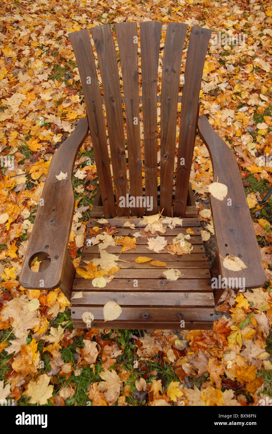 Une chaise avec des feuilles se trouve entre les feuilles tombées à l'automne dans le Vermont. Banque D'Images