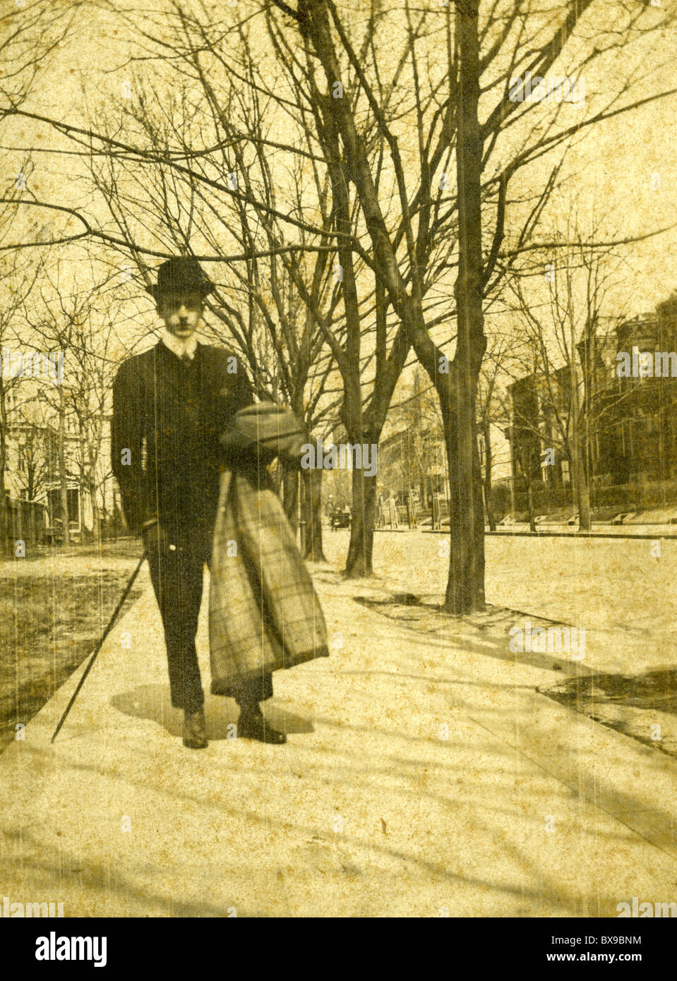 L'homme vêtu de noir hat fashion marche sur trottoir au cours de années 1890 en noir et blanc Americana Banque D'Images