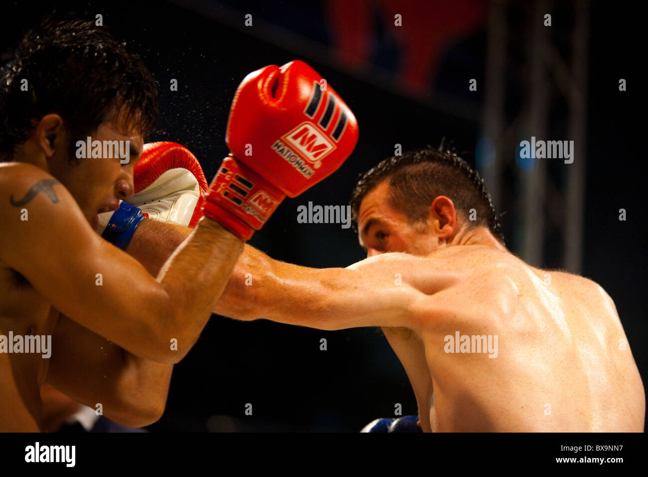 Coup gauche du portrait Le muay thai fighter landing sur la face de l'adversaire de kickboxing amateur asiatique à une lutte Banque D'Images