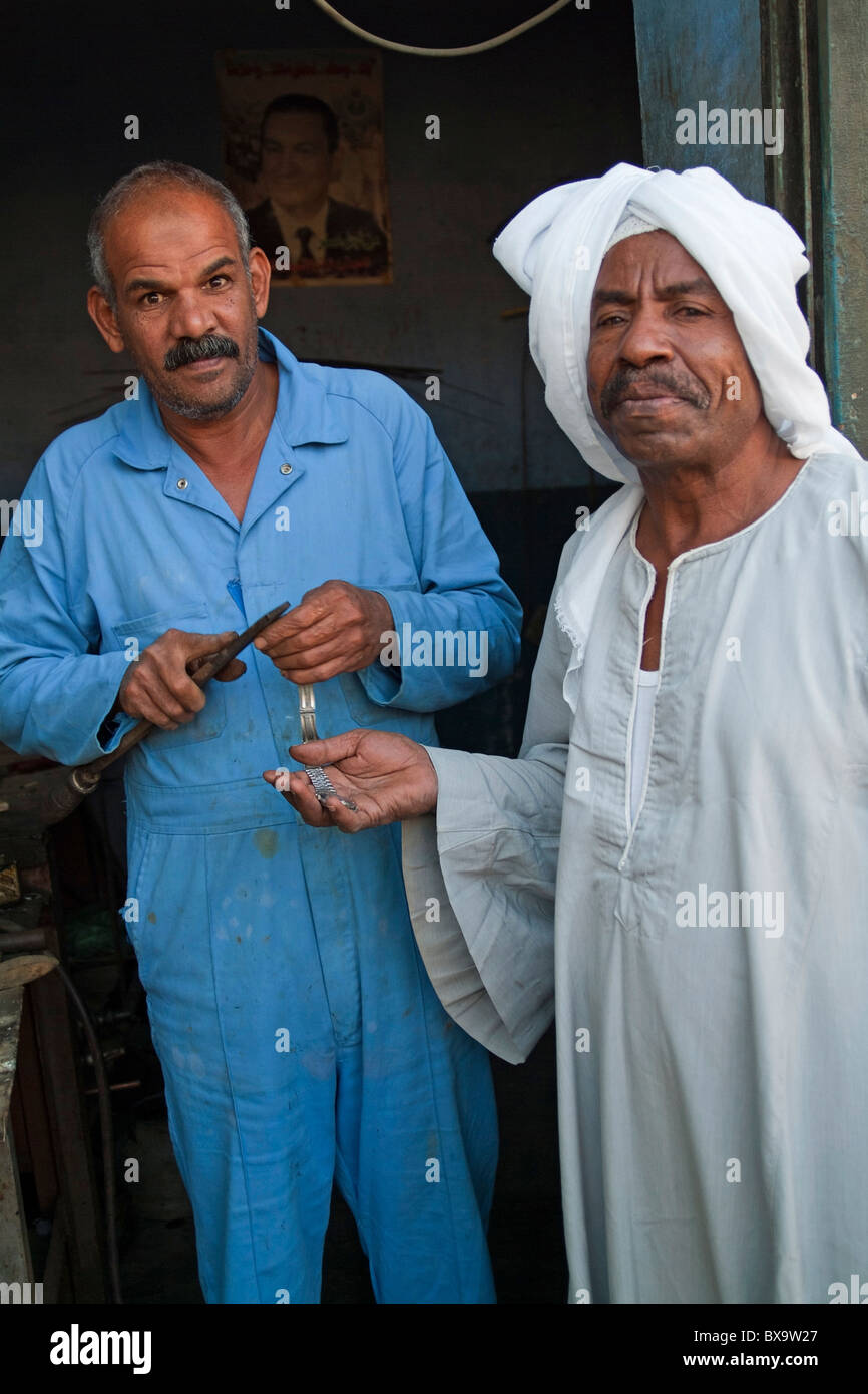 Les réparations de l'homme le bracelet de son client aux côtés d'attente, Quoseir Village, Mer Rouge, Egypte. Banque D'Images