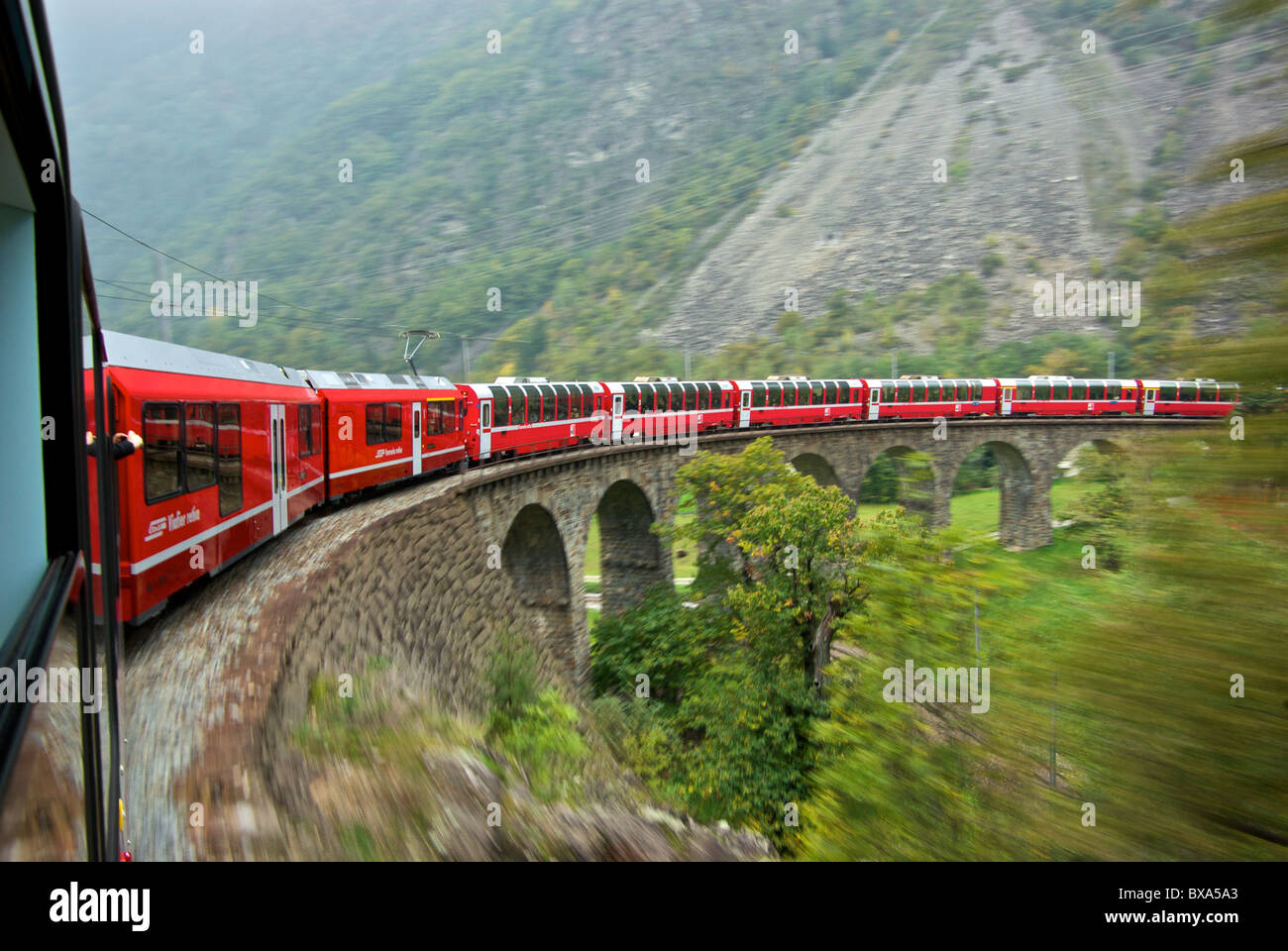 Paysage dans le flou d'autorails panoramiques de fer rhétique train Bernina Express sur viaduc circulaire près de Brusio Italie Banque D'Images