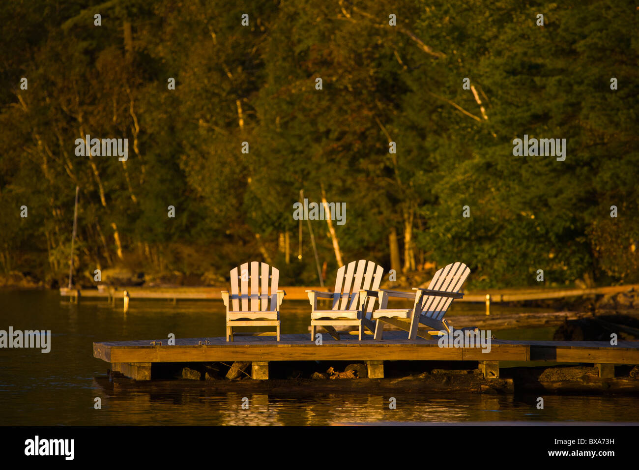 Des chaises au coucher du soleil sur un quai dans le lac d'entrée en quatrième dans les montagnes Adirondack de New York Banque D'Images