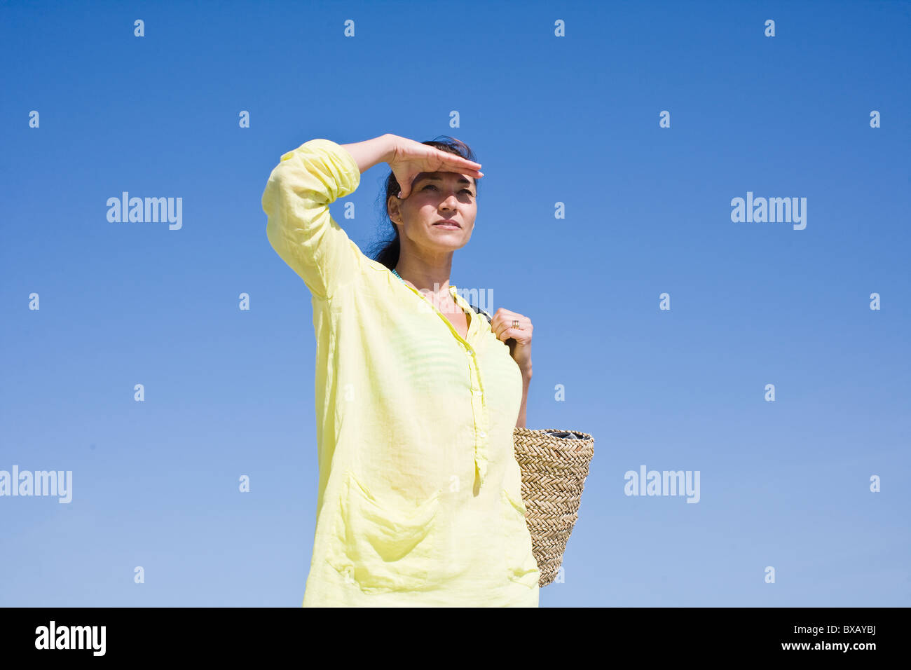 Femme portant le sac de plage et de blindage yeux Banque D'Images