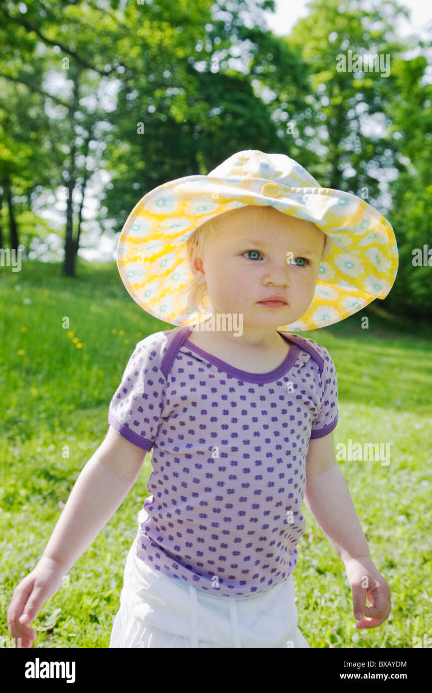 Girl wearing spotted sun hat standing in meadow Banque D'Images