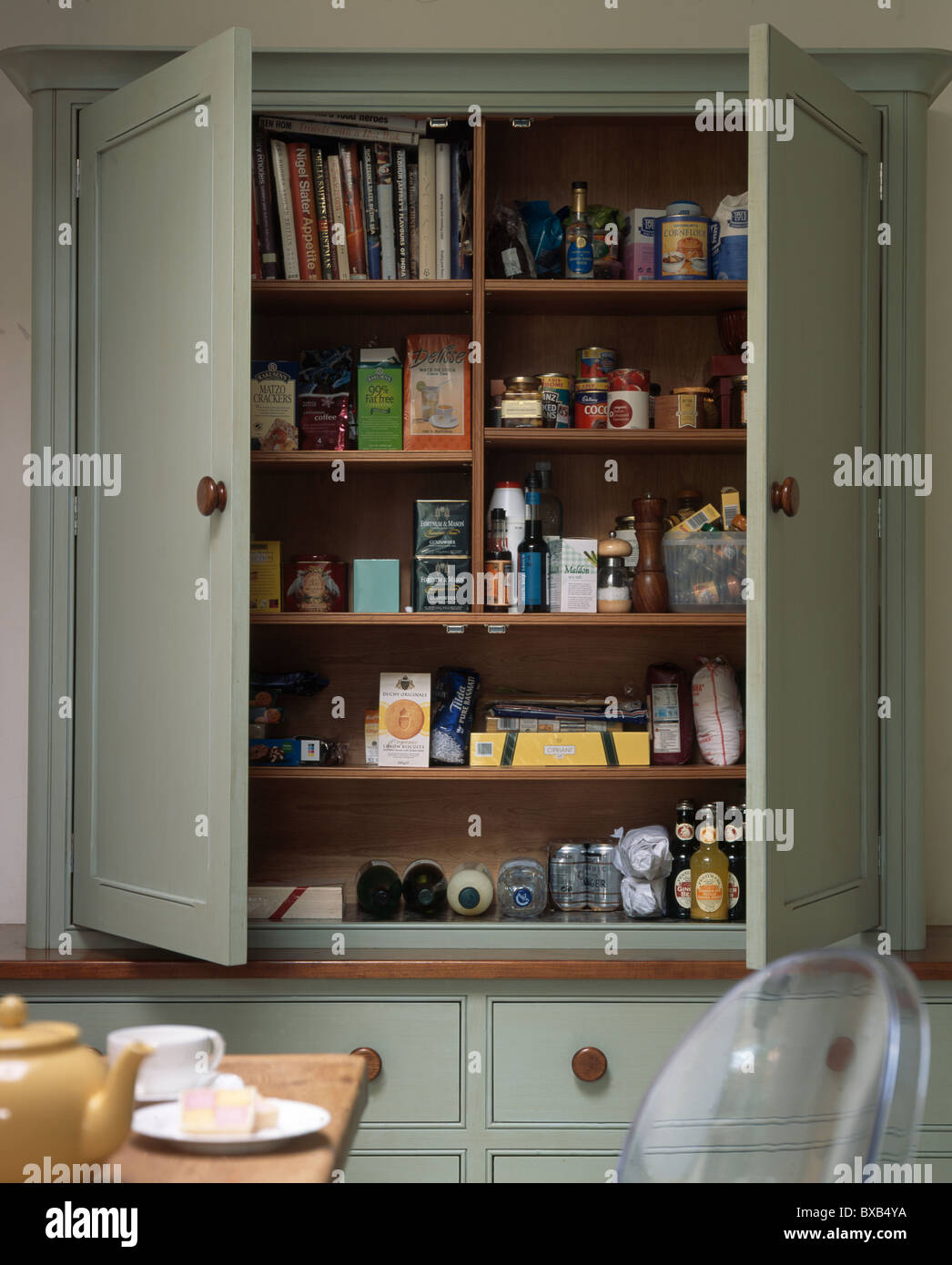 Close-up de vert pâle armoire de cuisine avec des portes s'ouvrent sur l' épicerie et des livres de cuisine sur des étagères Photo Stock - Alamy