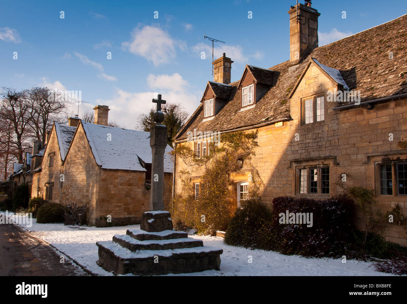 La croix à l'extérieur contre chalet dans le village de Cotswold Stanton, Gloucestershire, Angleterre. Banque D'Images