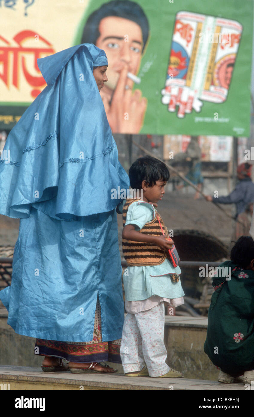 Le BANGLADESH. Mère ET FILS DANS LES RUES DE DHAKA SOUS LE PANNEAU PUBLICITAIRE Banque D'Images