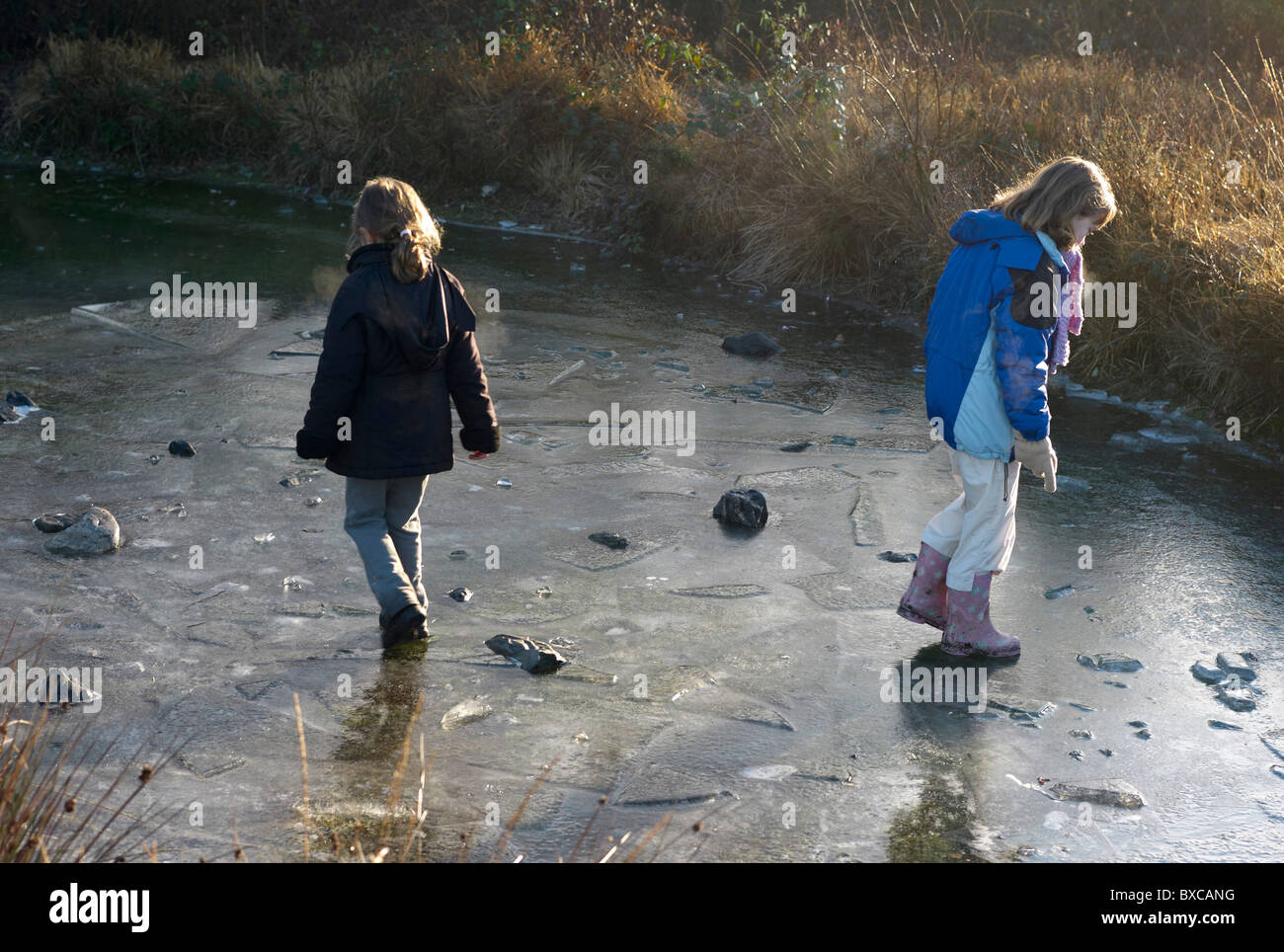 Deux enfants jouant sur la glace sur un étang gelé dans le Devon en Angleterre Banque D'Images