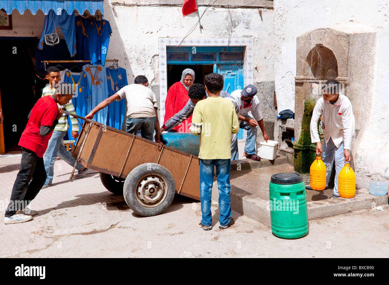 Un groupe de personnes loading récipients d'eau dans la Médina d'Essaouira, Maroc, Afrique du Nord. Banque D'Images