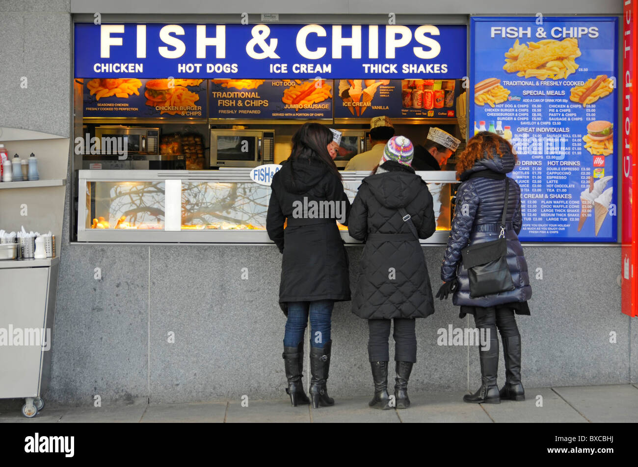 Fish and chips shop comptoir vue arrière groupe touristique de clients magasiner pour la cuisine britannique traditionnelle par les personnes visitant la Tour de Londres Angleterre Royaume-Uni Banque D'Images