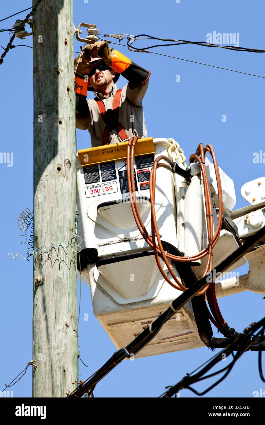 Travailleur de l'utilitaire dans un seau de travailler sur des lignes électriques. Banque D'Images Travailleur de l'utilitaire dans un seau de travailler sur des lignes électriques. Banque D'Images