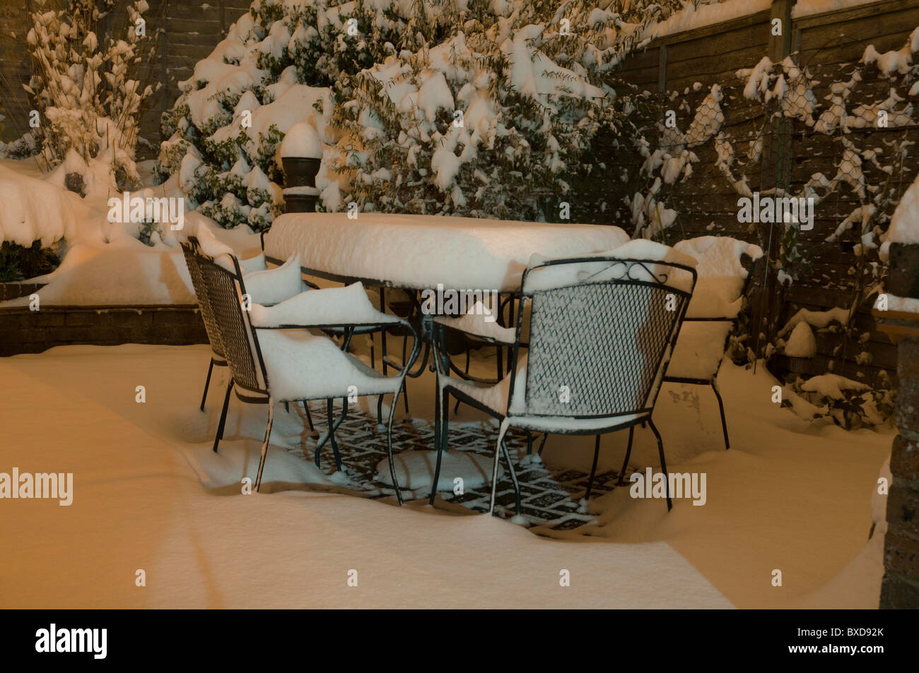 Snow garden patio ensemble de chaises et de table entre des arbres et arbustes couverts blanc Banque D'Images