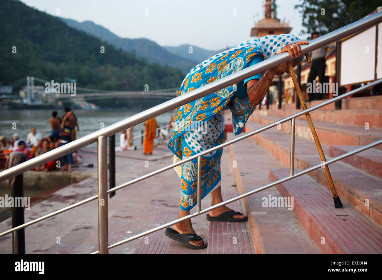 Vieille Femme clims les étapes d'un ghat sur la sainte Gange à Rishikesh, Uttarakhand, Inde. Banque D'Images