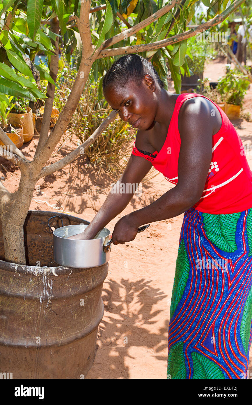 Jeune femme se lave pot après la cuisson le dîner dans le village de Simoonga près de Livingstone, Zambie Afrique. Banque D'Images