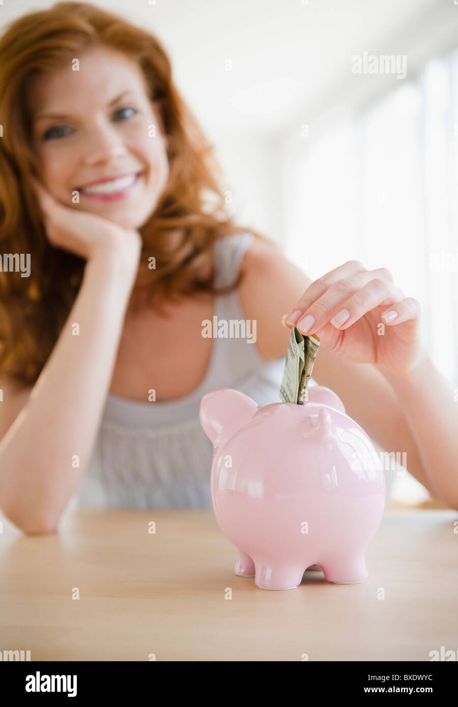Woman putting money in piggy bank Banque D'Images