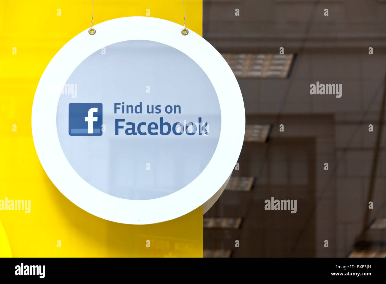 Facebook signe, avec logo rond, suspendu dans la fenêtre de magasin, 'nous sommes sur Facebook" Banque D'Images