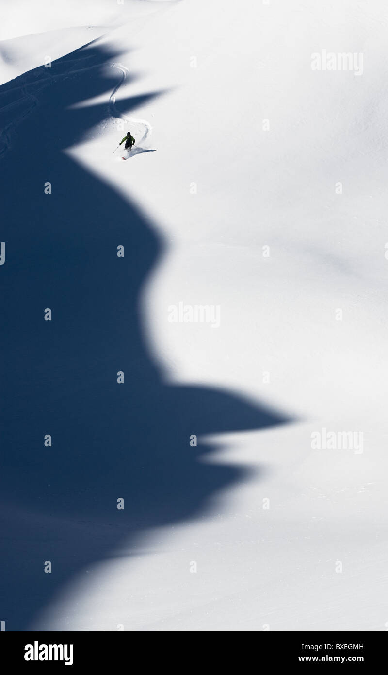 Un skieur de télémark de prendre un virage en poudre en Disentis, Suisse. Les montagnes ont jeté une ombre qui ressemble à un profil d'homme. Banque D'Images