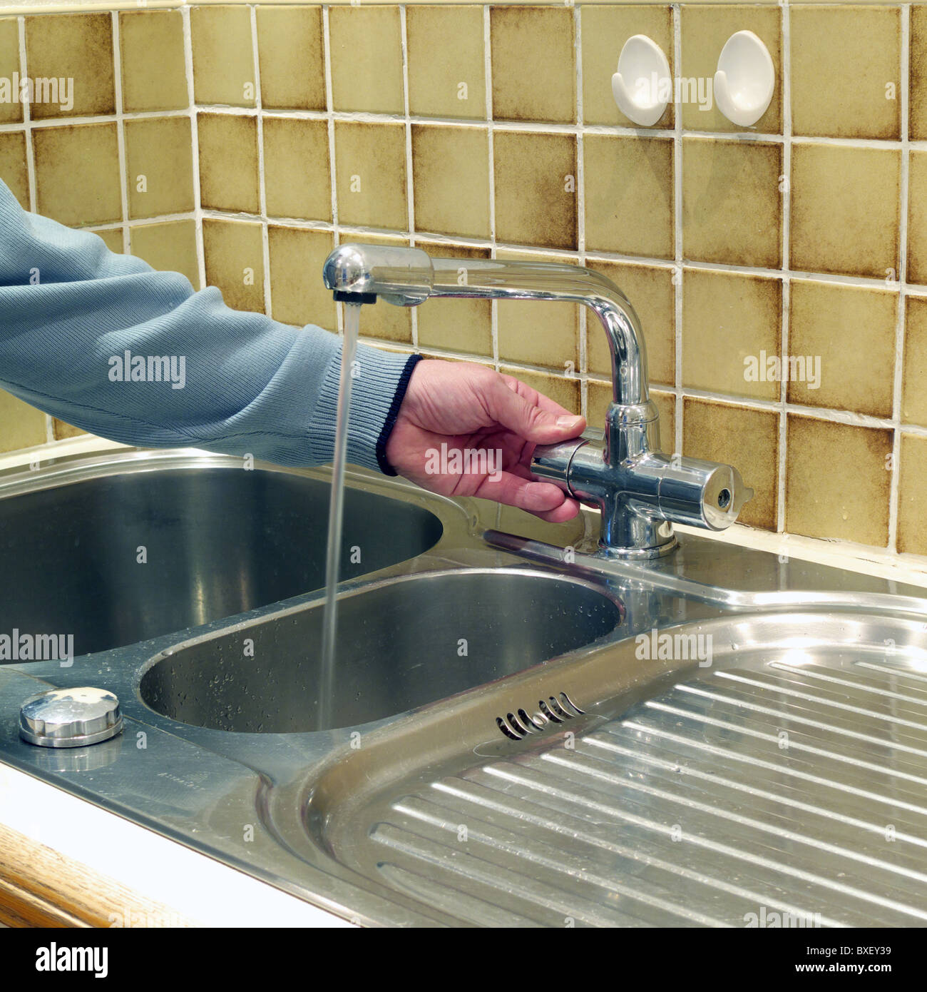 Homme de race blanche d'allumer le robinet mélangeur robinet ( ) à un évier  de cuisine dans un environnement domestique, MODÈLE BRITANNIQUE PUBLIÉ  Photo Stock - Alamy