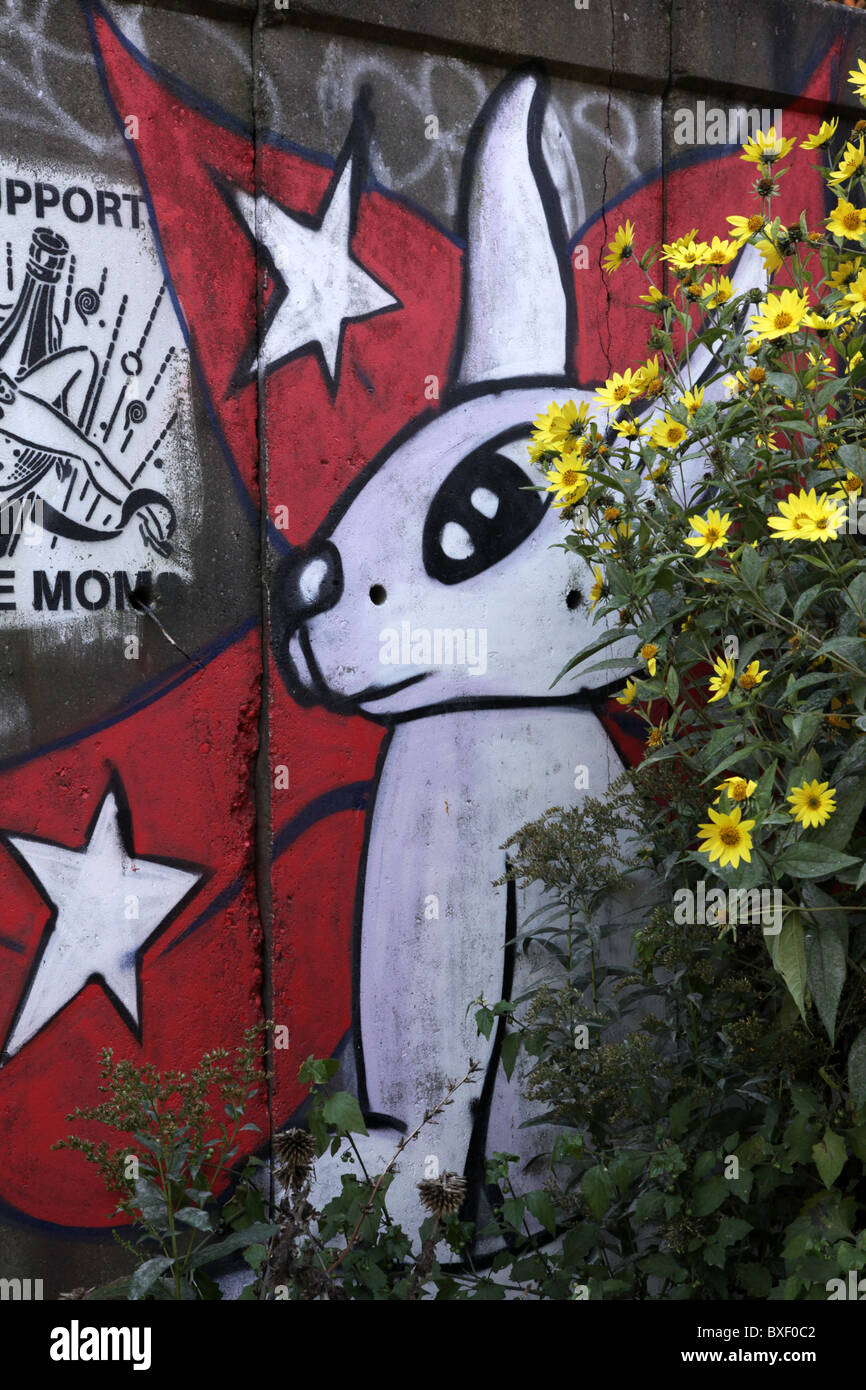 Graffiti sur un mur à Amsterdam d'un lapin blanc, bordé de fleurs et arbustes Banque D'Images