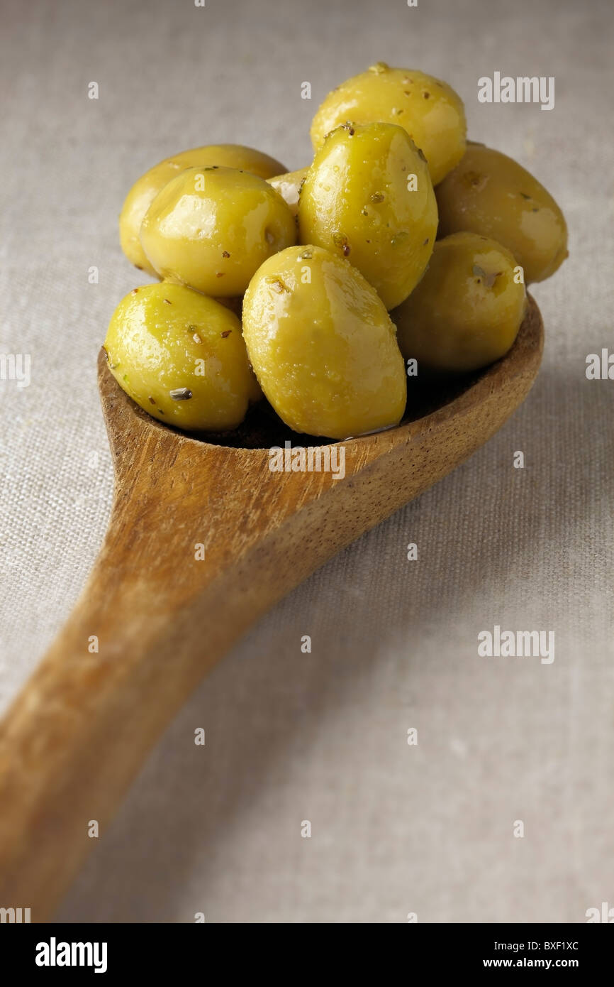 Olives vertes sur cuillère en bois Banque D'Images