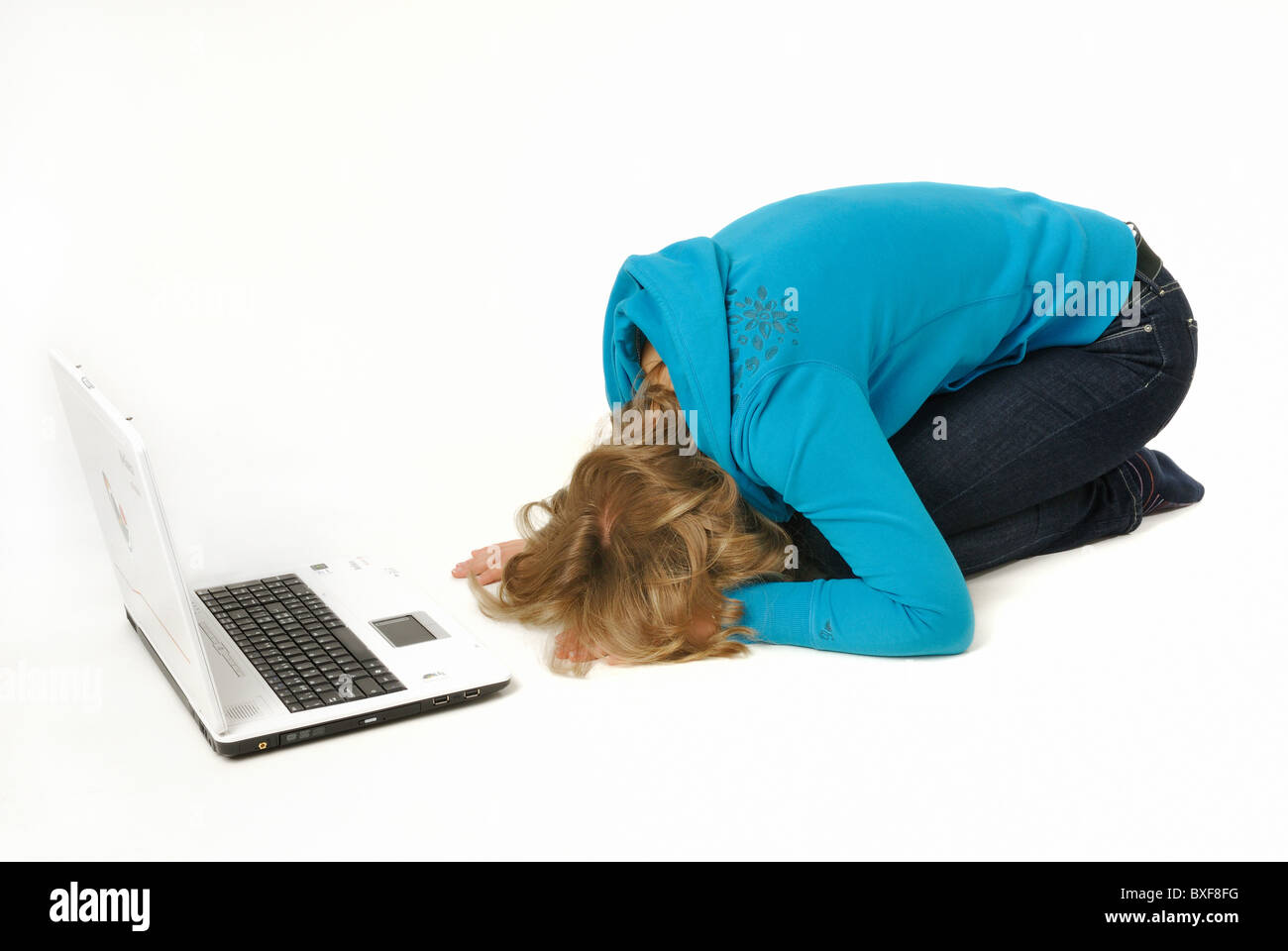 Jeune femme en s'inclinant devant un ordinateur portable, d'adorer le veau d'or..... Banque D'Images