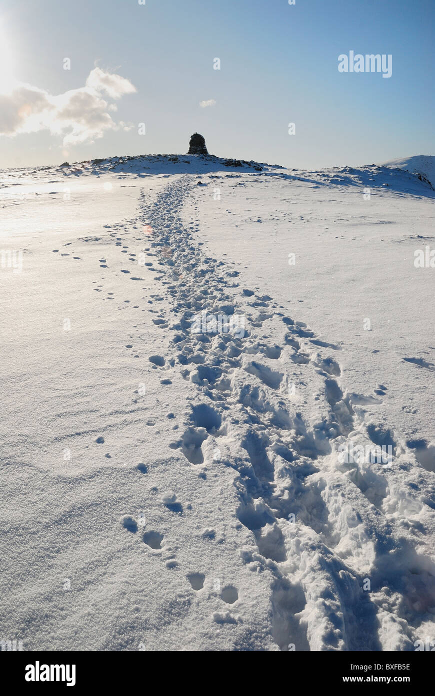 Des traces de pas dans la neige vers le sommet en haut cairn espion du Lake District Banque D'Images