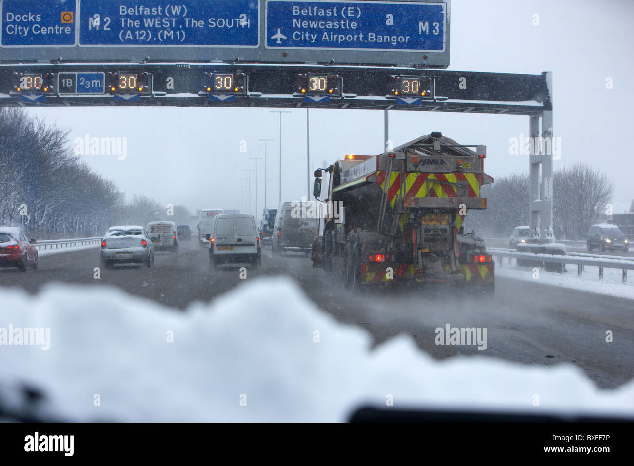 Le sablage des chasse-neige camion descendant d'autoroute sur un jour froid des hivers enneigés de l'Irlande du Nord Belfast Banque D'Images