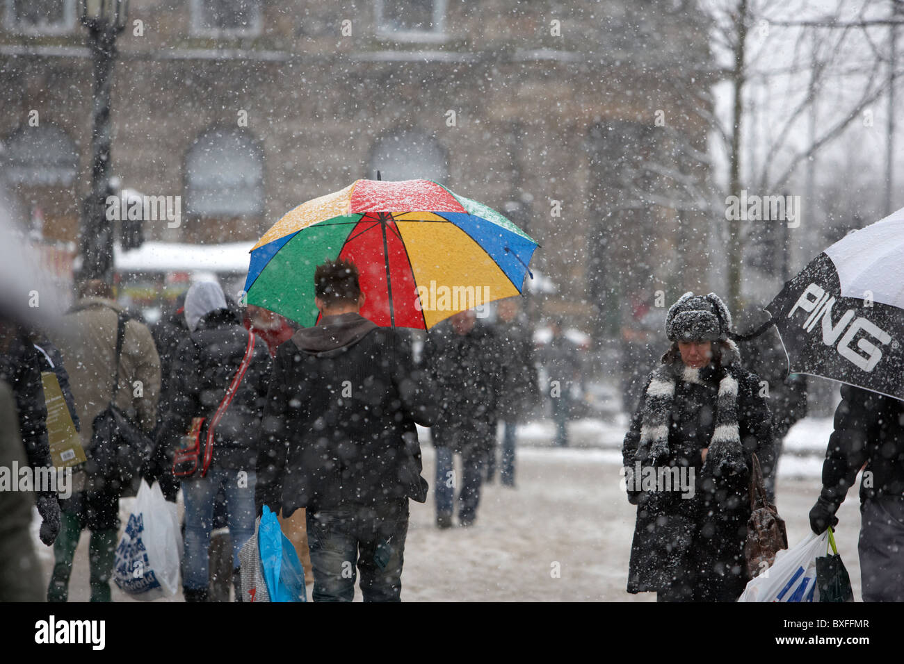 L'homme à l'ombrelle colorée shopping de Noël sur un jour froid des hivers enneigés de l'Irlande du Nord Belfast Banque D'Images