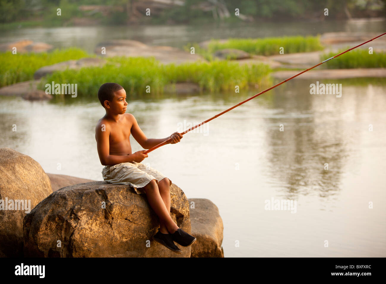 African American boy la pêche dans le lac Banque D'Images