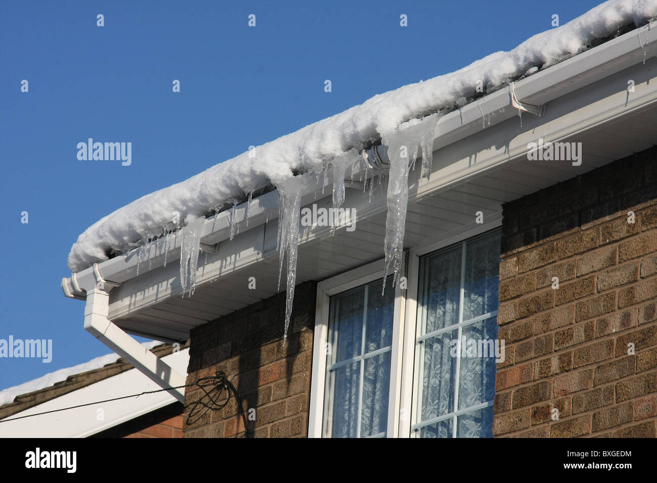 Les glaçons pendant de la gouttière de toit maison par temps très froid. Banque D'Images