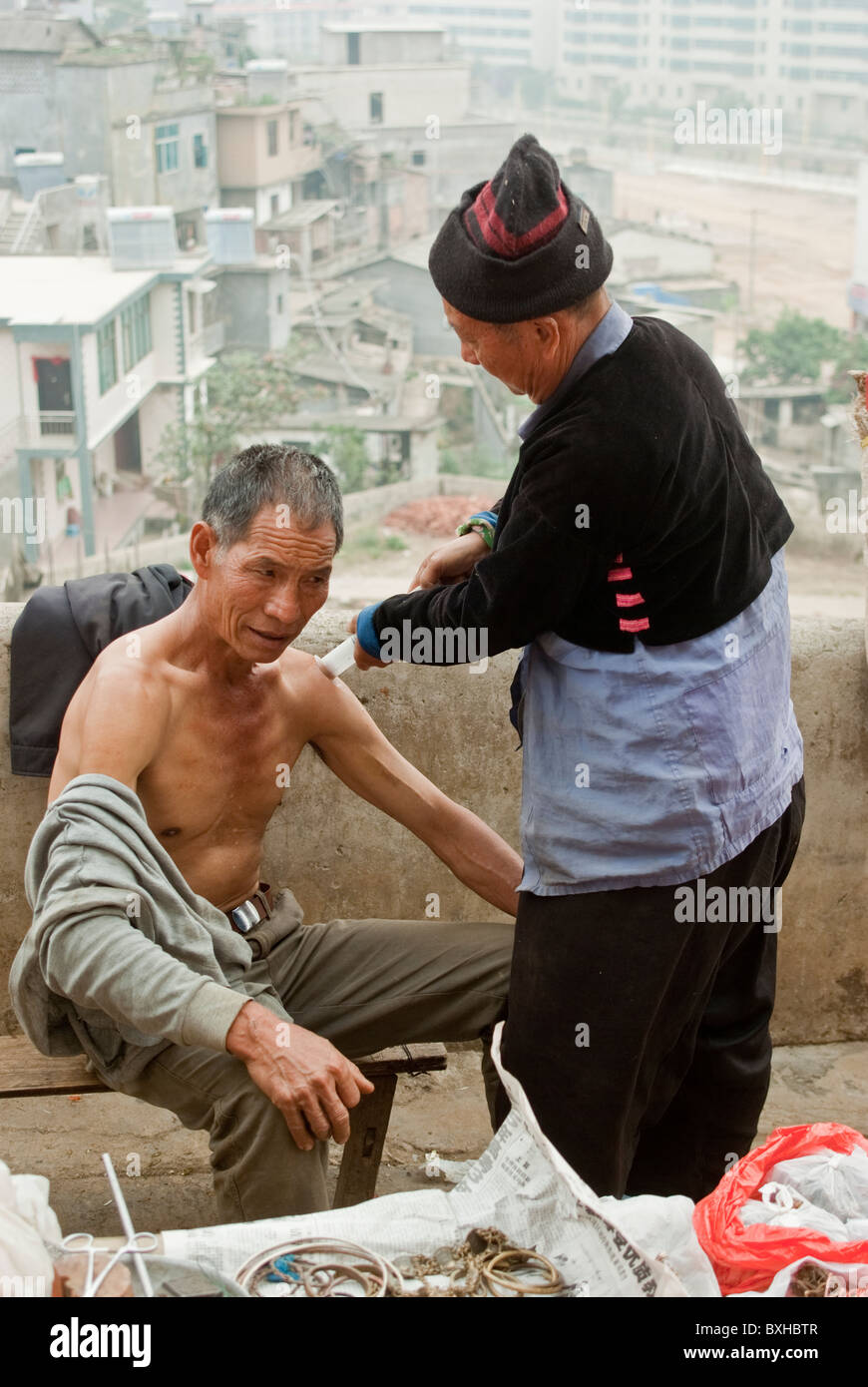 L'Asie, Chine, Yunnan, Honghe Préfecture, Jinping. L'homme reçoit un traitement aux ventouses le jour du marché. Banque D'Images