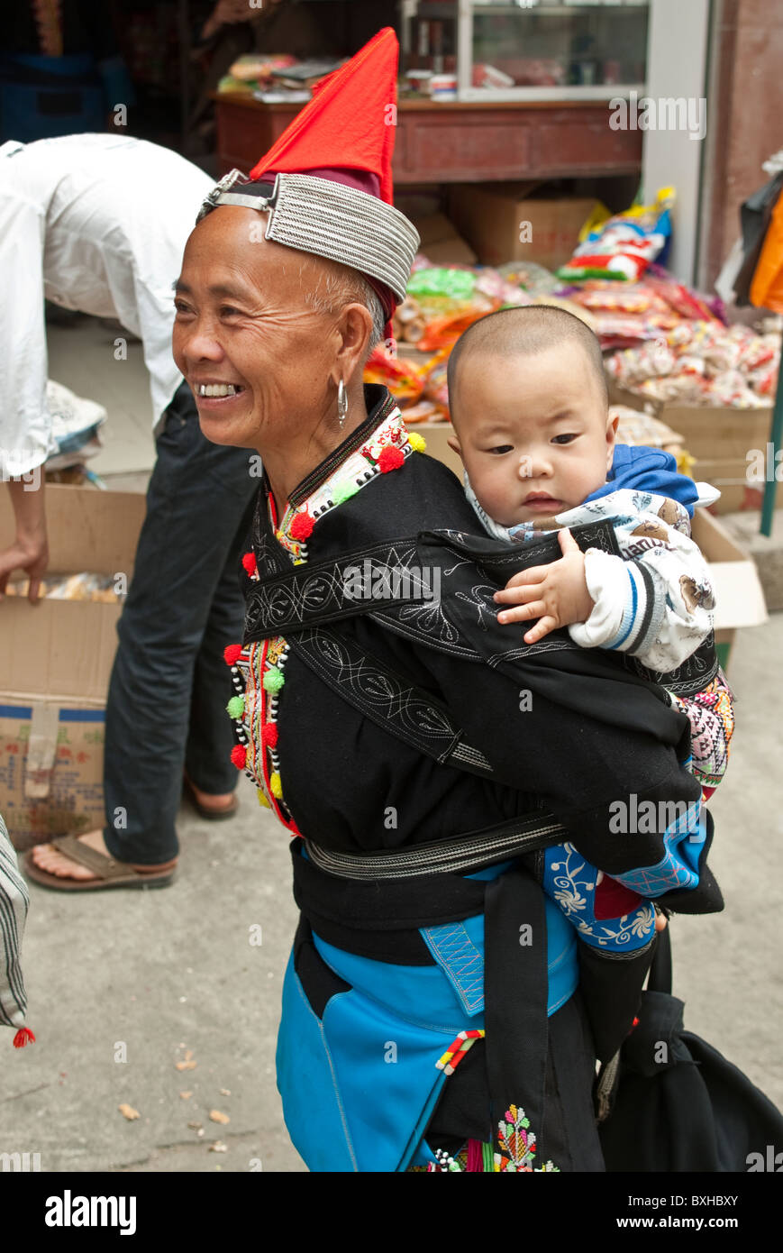 L'Asie, Chine, Yunnan, Honghe Préfecture, Jinping. Tête rouge Yao femme avec bébé en sac à dos. Banque D'Images